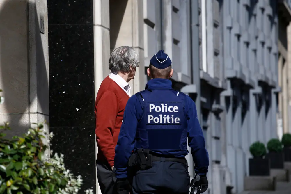 Policier belge en discussion avec un citoyen, illustrant le rôle de contact et d'information des agents de terrain.
