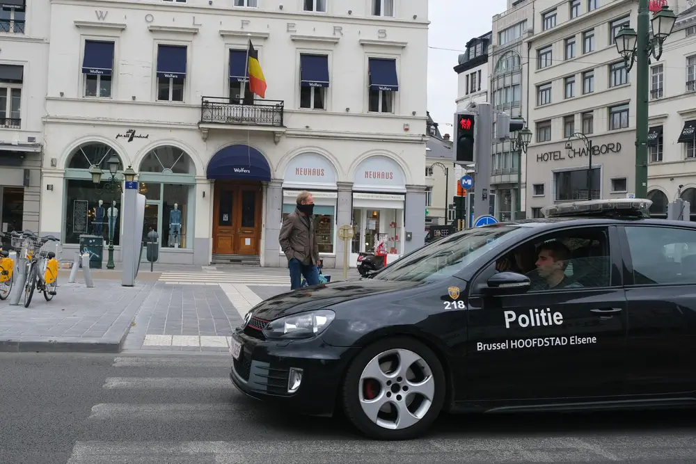 Voiture de police belge noire de la zone Bruxelles-Capitale circulant en ville devant des enseignes.