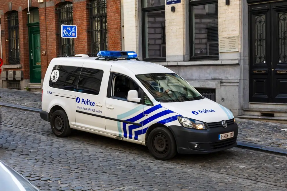 Fourgon de la police de Bruxelles-Capitale Ixelles en patrouille de quartier dans une rue pavée résidentielle.