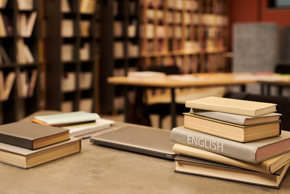 Voorbereidingsboeken, studiemateriaal en computer op een bureau om te oefenen voor de selectietesten.