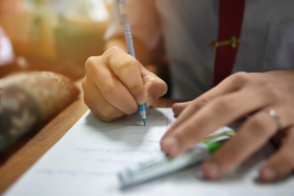 Kandidaat in uniform die geconcentreerd schrijft tijdens een schriftelijke selectieproef voor de politie.