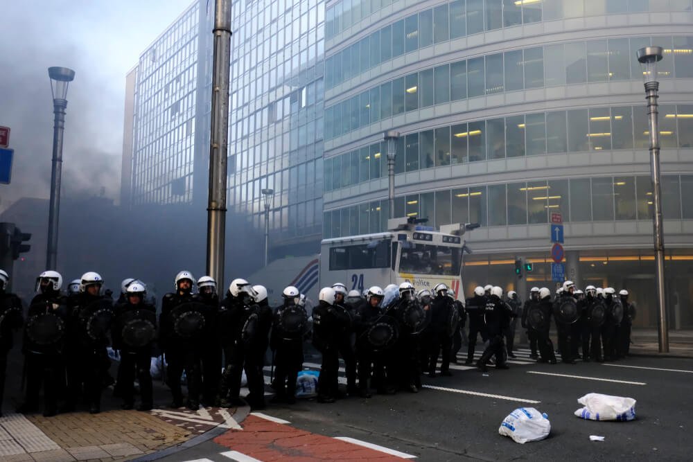 Interventieteam van de politie met schilden en sproeiwagen, als voorbeeld van zelfbeheersing en stressbestendigheid.