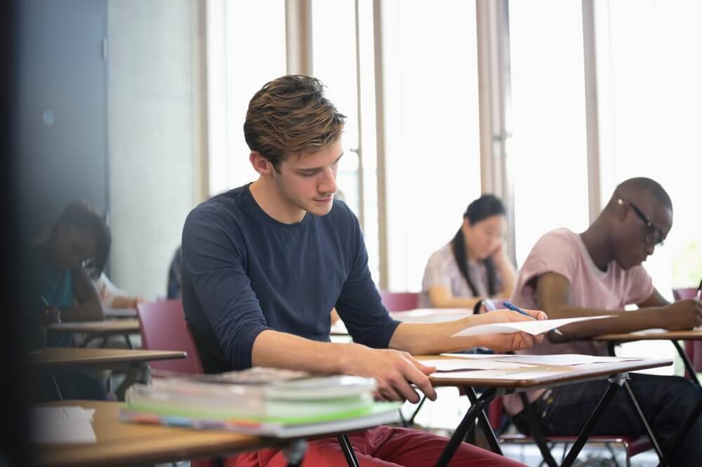 Kandidaten leggen geconcentreerd hun cognitieve selectieproeven af in een examenlokaal voor de politie.