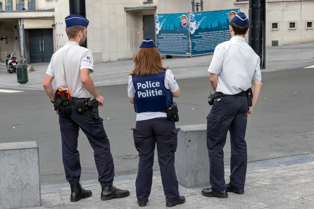Gemeenschapswachten in uniform op de rug gezien, ter illustratie van burgerdialoog en buurtbemiddeling.
