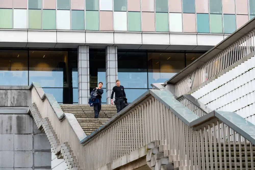 Deux agents de la DSU descendant les marches du quartier général de la police fédérale, un bâtiment fédéral moderne.