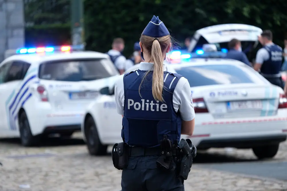 Politieagent in uniform die zijn politie-embleem toont voor de nationale vlag