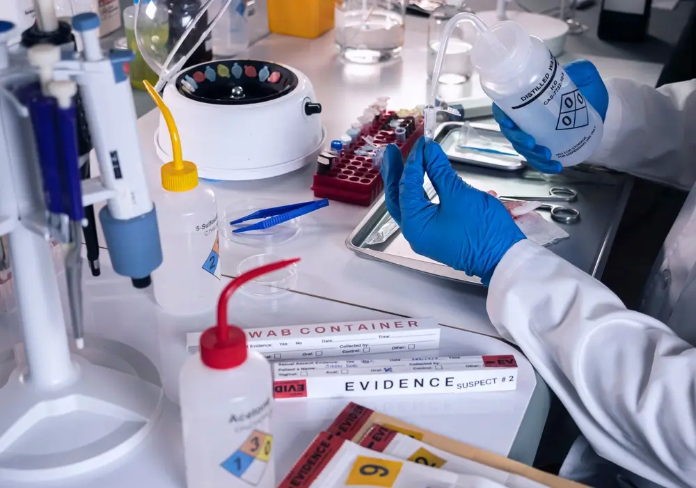 Aspirant in opleiding tot forensisch onderzoeker die bewijsmateriaal behandelt in het laboratorium van de politieacademie.