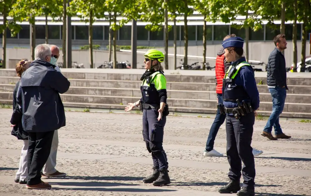 Policières fédérale et locale en uniforme discutant avec des citoyens lors d’une opération de contrôle en Belgique.