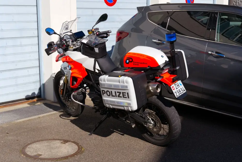 BMW-politiemotor met blauw zwaailicht, sirenes en officiële koffers voor interventies en snelwegpatrouilles.