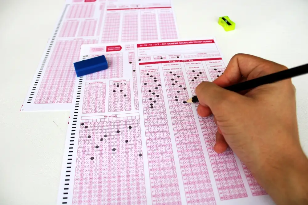 Candidat complétant une feuille de réponses lors d'un test de sélection écrit pour évaluer ses aptitudes cognitives.
