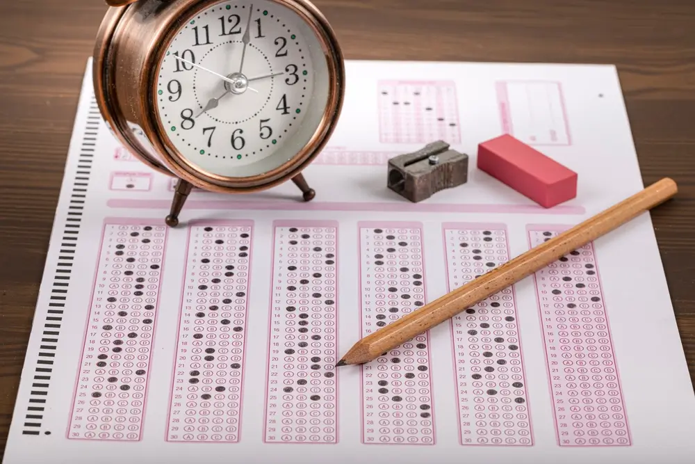 Selectie-examen voor de werving bij de politie met een meerkeuzevragenlijst, een potlood en een wekker.