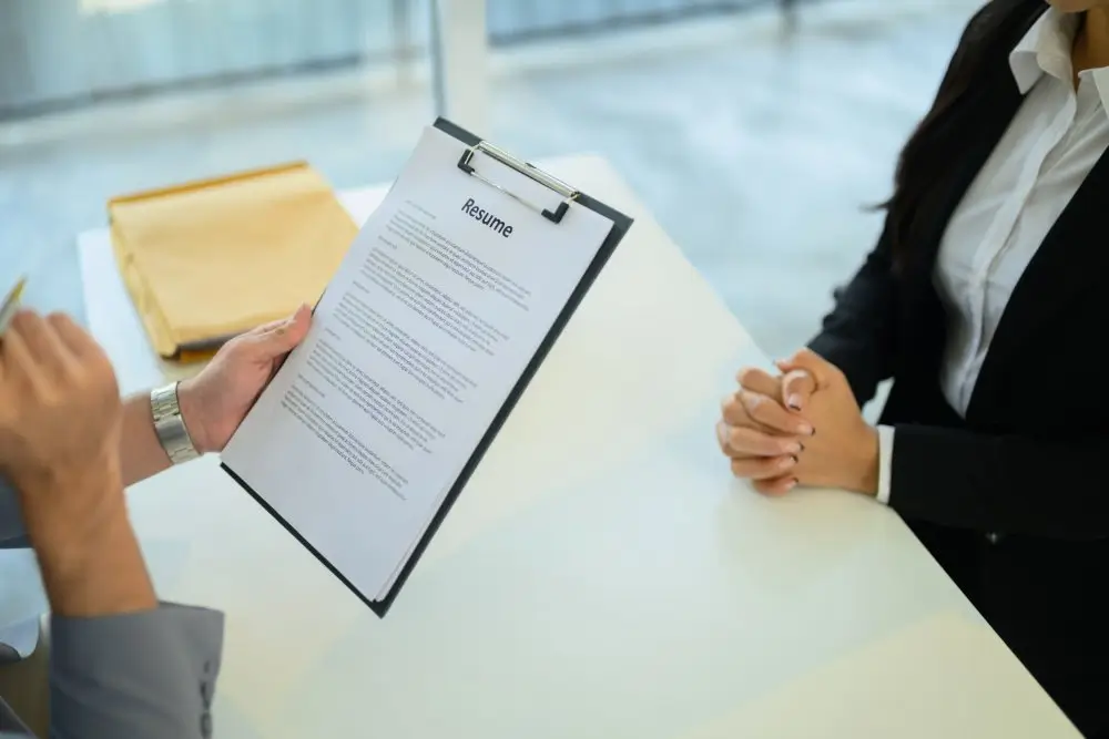 Recruteur analysant le CV d'un candidat lors d'un entretien pour une évaluation professionnelle des compétences.