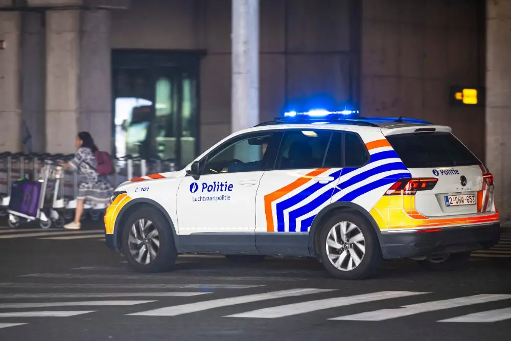 Véhicule de police belge avec gyrophare bleu affichant le badge et l'emblème officiel des forces de l'ordre.