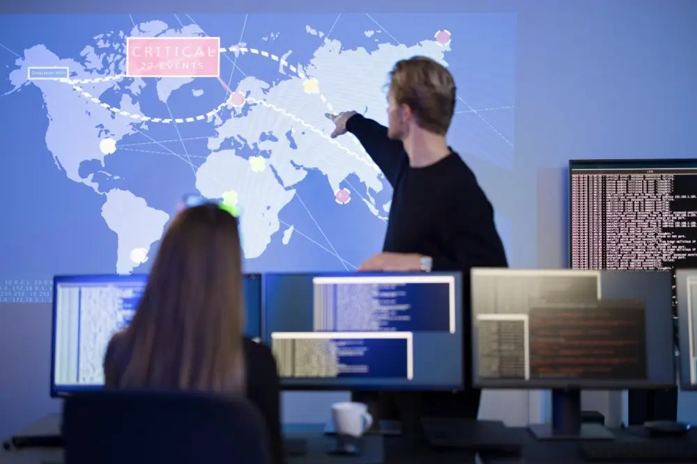 Agenten van de computercrime-eenheid analyseren een wereldkaart in de operatiezaal voor computerschermen.