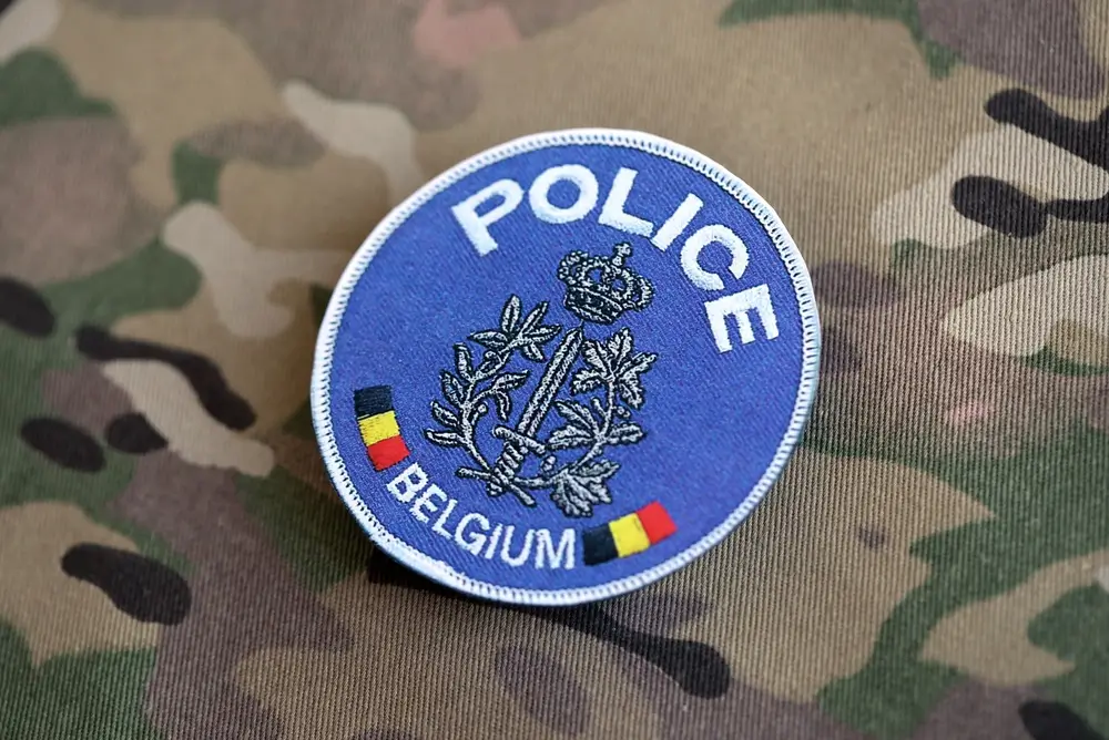 Geborduurd embleem van de Belgische politie met de vermelding Belgium op een tactisch uniform.