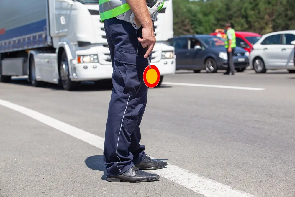 Inspecteur van de Wegpolitie in uniform met verkeersbord tijdens een gerichte verkeerscontrole op de snelweg.