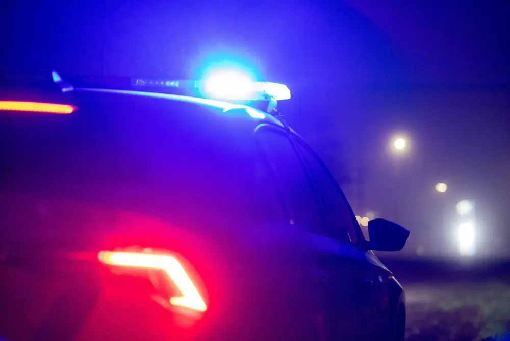 Politievoertuig met blauwe zwaailichten tijdens een nachtelijke speekseltestcontrole op de weg
