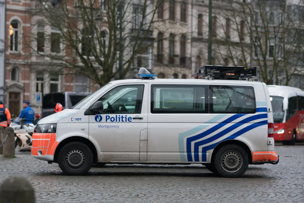 Fourgon de patrouille de la police belge avec stripping orange et bleu, illustrant l'équipement d'intervention mobile.